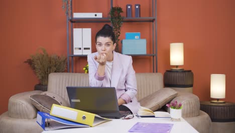 Home-office-worker-young-woman-biting-her-nails-looking-at-camera.